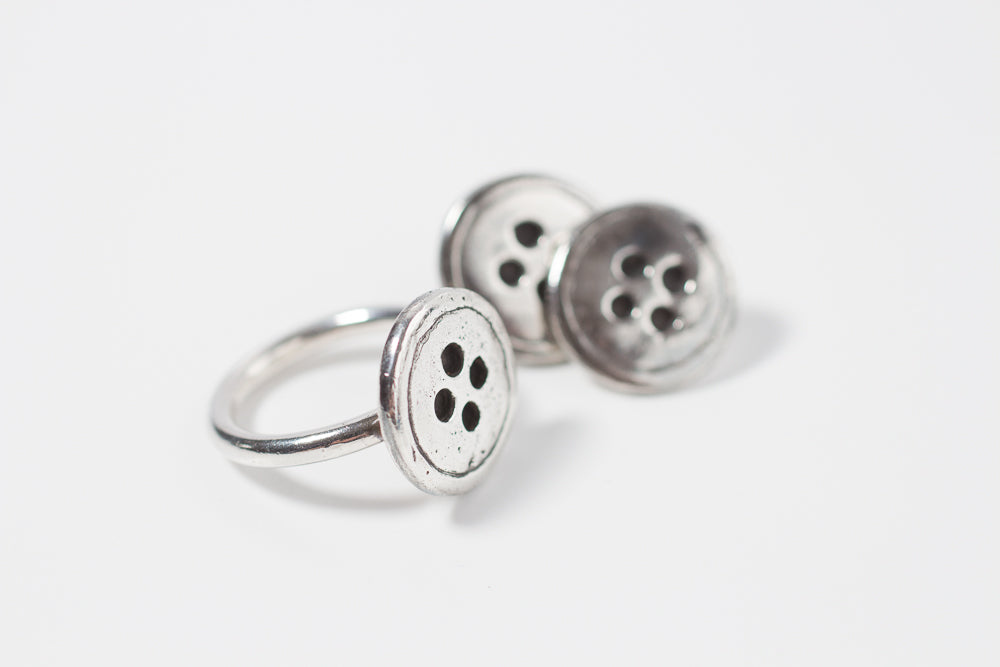 A silver-colored ring with three button-shaped embellishments on the top.