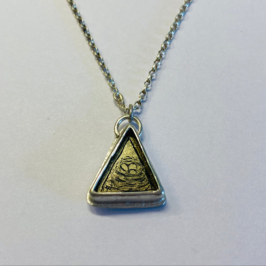 Necklace with a triangular pendant depicting a birds nest with eggs.